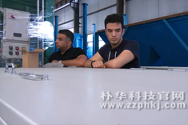 伊朗客户在朴华科技车间参观,双手放在光氧催化设备的顶盖上